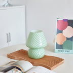 Green mushroom-shaped glass vase on a wooden tray.